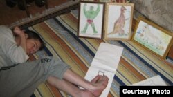 Денис Хасанов показывает, как он рисует ногами.  Фото из личного архива семьи Хасановых.