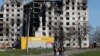 Local residents walk past a destroyed apartment building in Mariupol on April 20. 