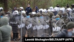 Polşanyň howpsuzlyk işgärleri we Belarusyň serhet araçäklerindäki migrantlar.