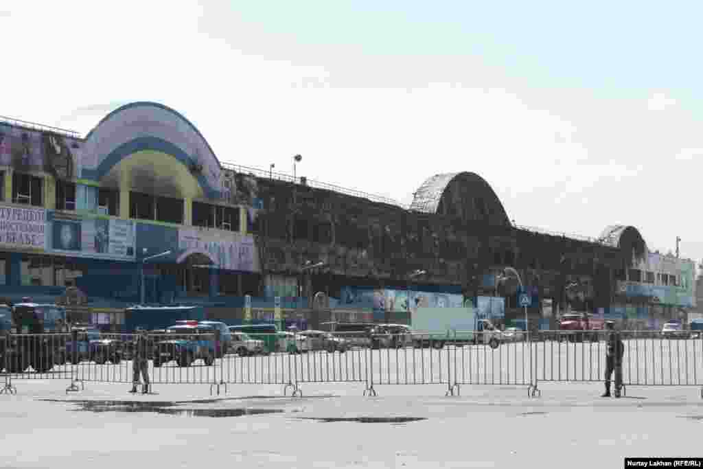 Сгоревшая территория торгового центра по-прежнему оцеплена.