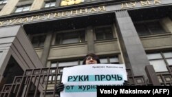 Москвада Думанын имаратынын алдында "Журналист аялдардан колуңарды тарткыла!" деген ураанды көтөрүп турган аял.  21-март, 2018-жыл. 