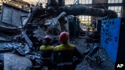 Рабочие стоят среди обломков поврежденной теплоэлектростанции ДТЭК после нападения России на Украину, 2 мая 2024 года