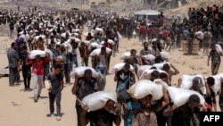 Жители на Газа пренасят чували с брашно, след като камиони с хуманитарна помощ навлязоха в северната част на ивицата.