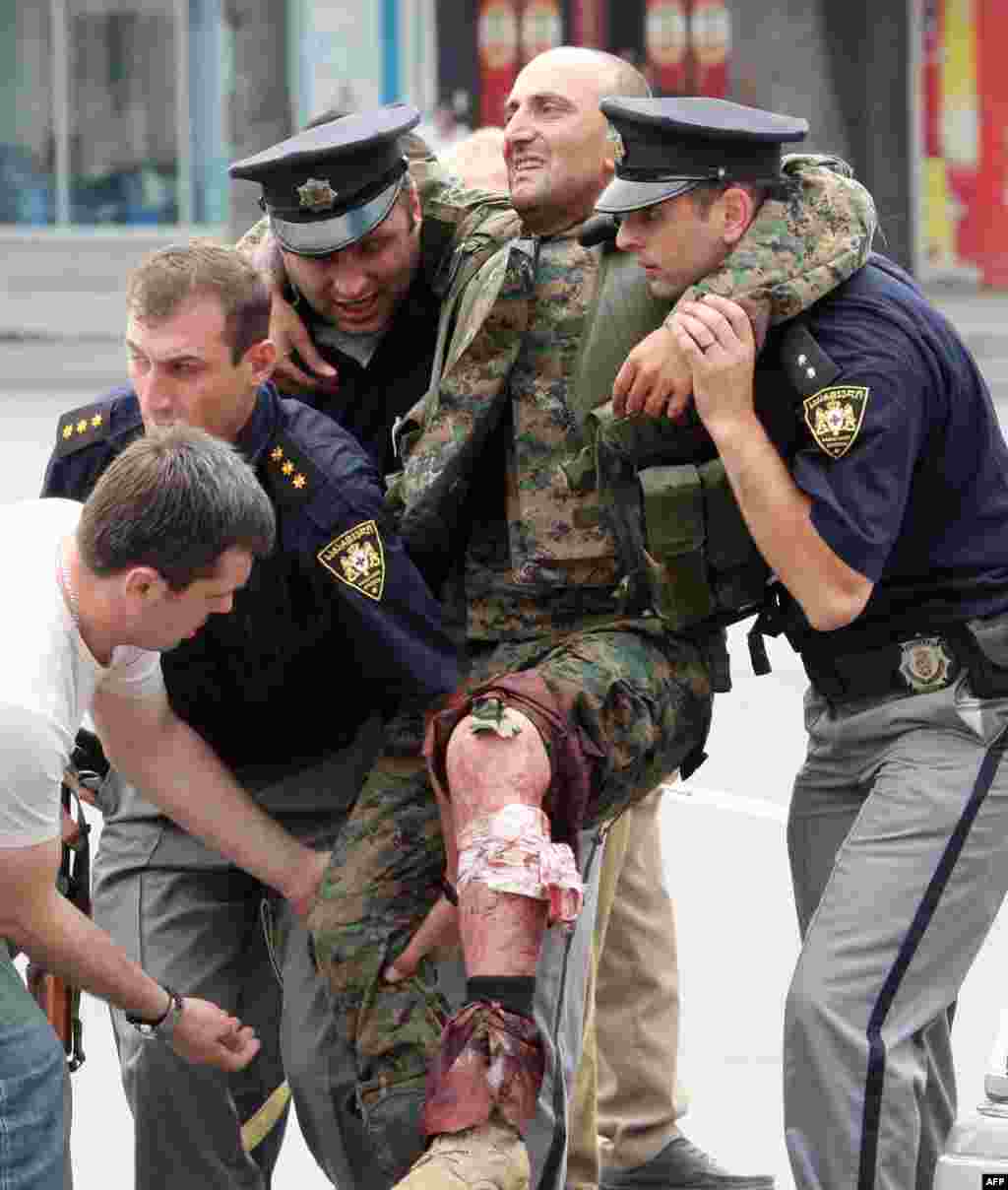 Полицейские оказывают помощь грузинскому солдату, раненному в бою с южноосетинскими сепаратистами в Гори, 8 августа 2008 года