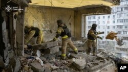 Ukrainanyň Adatdan daşary ýagdaýlar gullugy Ukrainanyň Sumy şäherinde 30-njy ýanwarda rus dron zarbasy bilen nyşana alnan köp gatly binada halas ediş işlerini geçirýär. 