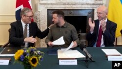 U.K. Prime Minister Keir Starmer (left) and Defense Secretary John Healey (right) applaud Ukrainian President Volodymyr Zelenskiy (center) after he addressed an extraordinary meeting of the British Cabinet on July 19. 