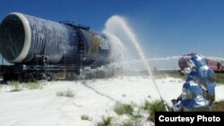 Сотрудники противопожарной службы ЧС обрабатывают цистерну с горючим специальной пеной, чтобы не произошло возгорания.  Таможенный пункт "Куланды", Жамбылская область, 16 июля 2014 года. Фото предоставлено ДЧС Жамбылской области.
