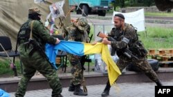 "Чыгыш" деген орусиячыл батальондун аскерлери Донецктеги өкмөттүк имарат алдында украин желегин айрып жатышат, 29-май, 2014