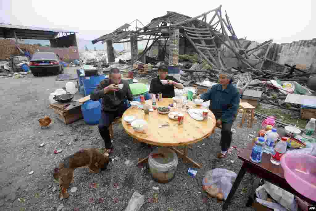 Китай &ndash; Місцеві жителі обідають біля свого пошкодженого землетрусом будинку. Яань, південно-західна провінція Сичуань, 22 квітня 2013 року