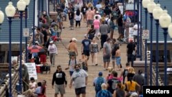 Коронавирус індеті өршіп тұрғанда жағалауда жүрген адамдардың арасында маска таққандары аз.  Калифорния, АҚШ. 22 маусым, 2020 жыл. Көрнекі сурет. 