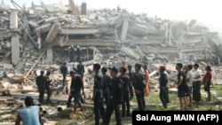 Люди наблюдают, как спасатели ищут выживших, оказавшихся под обломками обрушившегося здания в городе Мандалай, Мьянма, 29 марта 2025 года