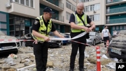 Police officers cordon off an area next to an apartment building damaged by a Russian attack in Kyiv on June 24. 