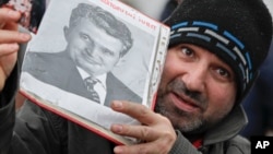 Мужчына трымае партрэт румынскага камуністычнага дыктатара Нікалае Чаўшэску з тэкстам «Пашана любімаму лідэру». Бухарэст, 25 сьнежня 2019 года, праз 30 гадоў пасьля расстрэлу Чаўшэўску і яго жонкі Элены 